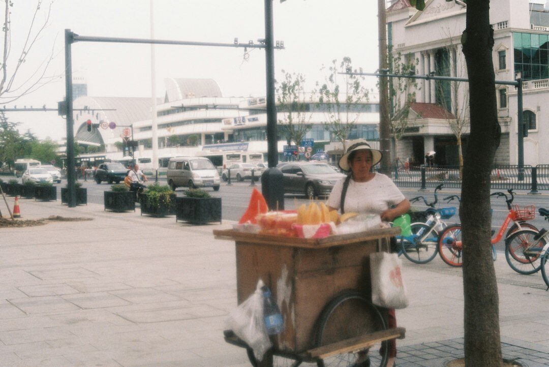 Elderly Chilean street vendor smiling behind a small fruit cart